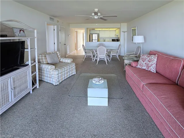 Carpeted living room with a ceiling fan