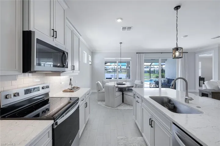 Kitchen featuring stainless steel appliances, white cabinets, backsplash, pendant lighting, and sink
