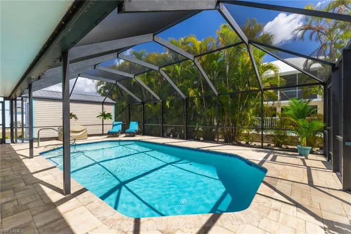 Outdoor pool featuring a sunroom, a patio, and glass enclosure