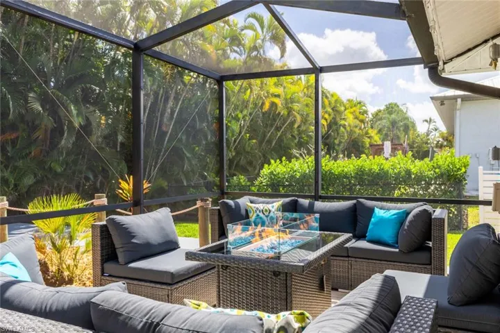 View of patio with an outdoor living space with a fire pit, a sunroom, and glass enclosure