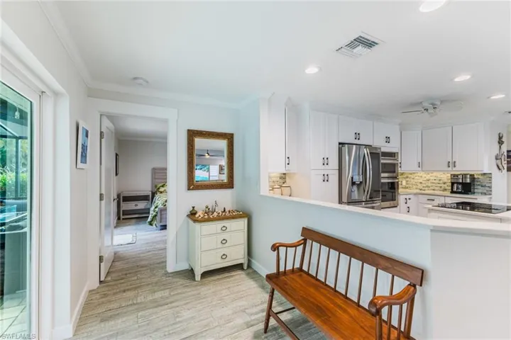 Kitchen with ceiling fan, backsplash, ornamental molding, stainless steel appliances, and white cabinetry