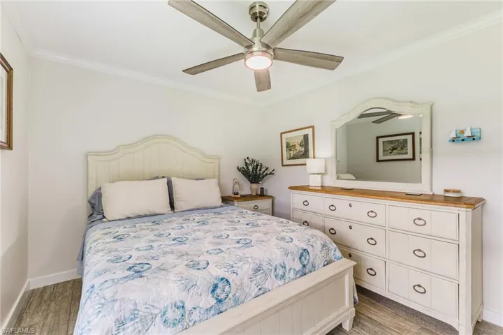 Bedroom with light wood finished floors, a ceiling fan, and crown molding