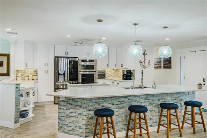 Kitchen with a breakfast bar area, decorative backsplash, stainless steel appliances, and ornamental molding