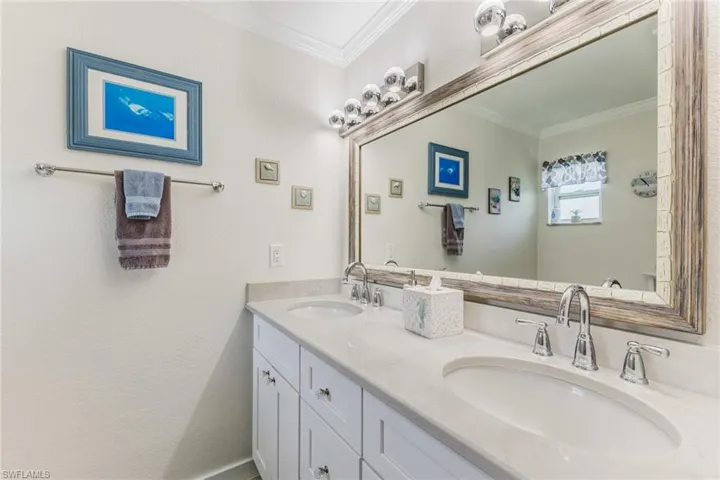 Bathroom with double vanity, ornamental molding, and a textured wall