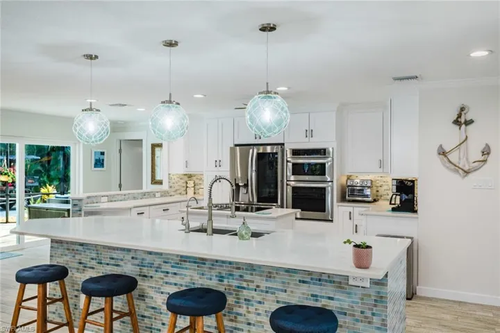 Kitchen with a kitchen bar, tasteful backsplash, stainless steel appliances, white cabinets, and light wood finished floors