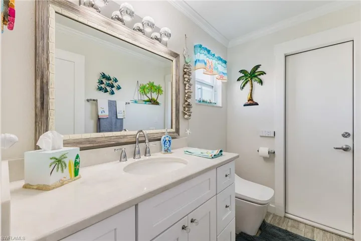 Bathroom with crown molding, vanity, and light wood-type flooring