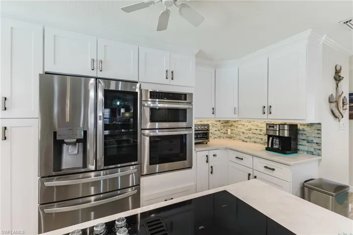 Kitchen featuring stainless steel appliances, decorative backsplash, a ceiling fan, dual tone cabinets, and crown molding