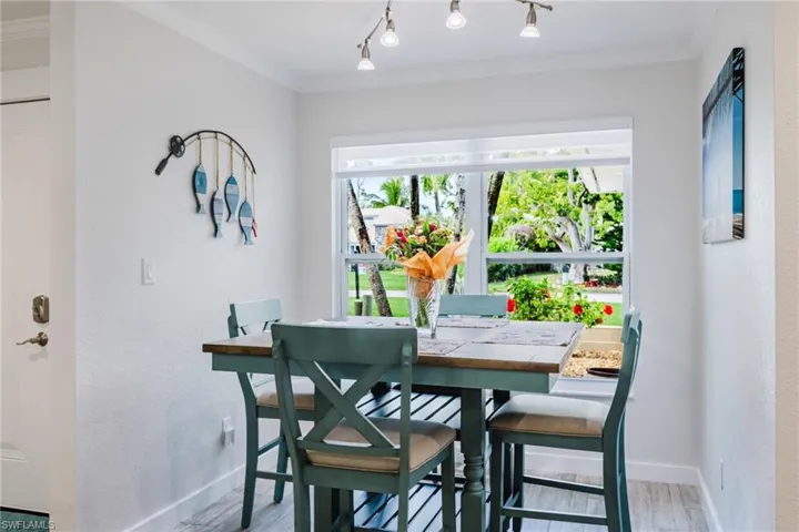 Dining space with ornamental molding, light wood finished floors, and a textured wall