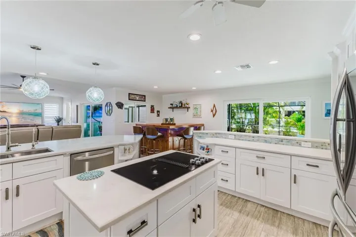 Kitchen featuring a ceiling fan, stainless steel appliances, white cabinetry, a kitchen island, and open floor plan
