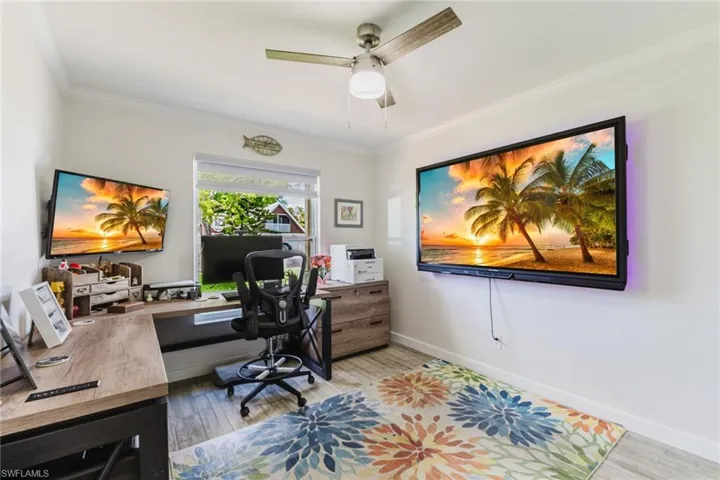 Office space with light wood-style floors, crown molding, and a ceiling fan