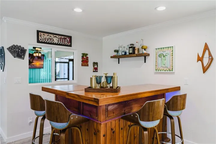 Indoor dry bar with butcher block counters, ornamental molding, open shelves, and recessed lighting