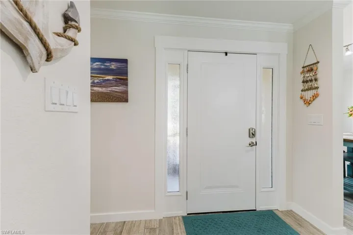 Foyer entrance featuring ornamental molding and light wood-style flooring