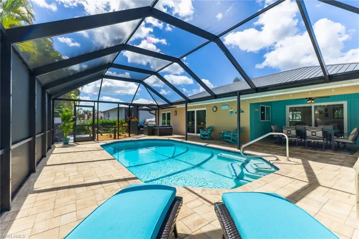 Swimming pool with a sunroom, a patio, outdoor dining area, and a lanai