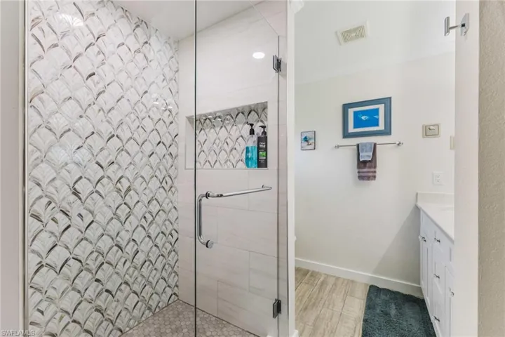 Full bath featuring vanity, a shower stall, ornamental molding, and light wood-style floors