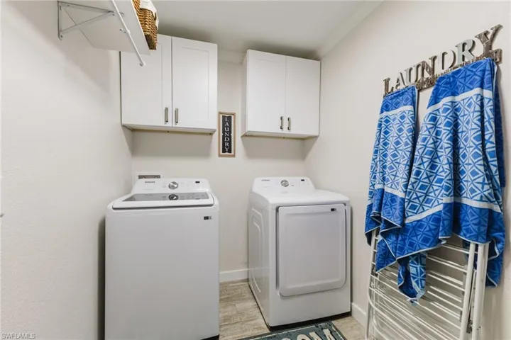 Laundry area featuring cabinet space, washing machine and dryer, light wood-style floors, and crown molding
