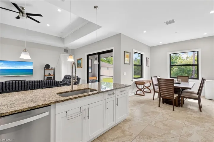 Kitchen island with a granite-style countertop and undermount sink, complemented by white shaker-style cabinetry and a stainless steel dishwasher