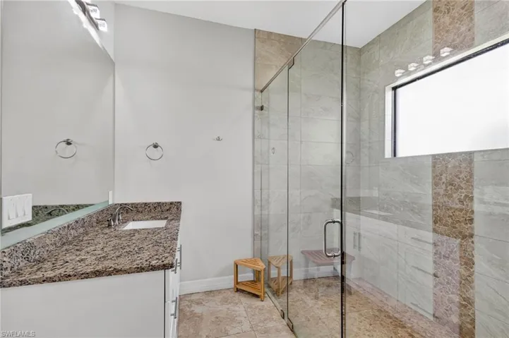 Walk-in shower with clear glass enclosure and built-in bench