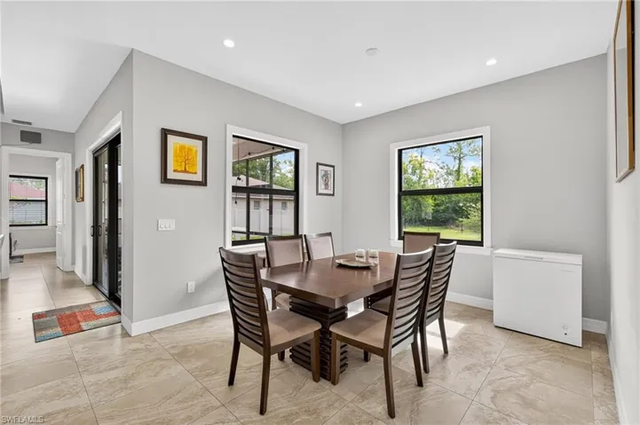 Spacious dining area featuring neutral wall tones, recessed lighting, large windows, and tile flooring