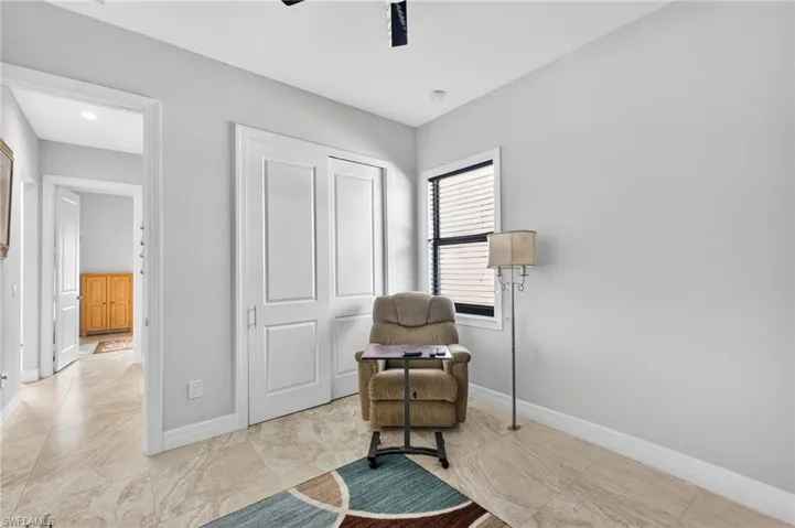 Light-toned tile flooring extends throughout this room, featuring light gray walls and a window with horizontal blinds