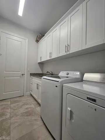 Laundry area featuring extensive white upper cabinetry and a coordinating white lower cabinet