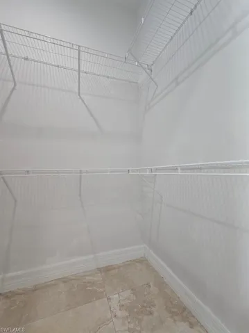 Walk-in closet featuring wire shelving, wire hanging rods, neutral wall paint, and square tile flooring