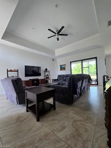 Tray ceiling with crown molding and recessed lighting, large format tile flooring, and sliding glass doors
