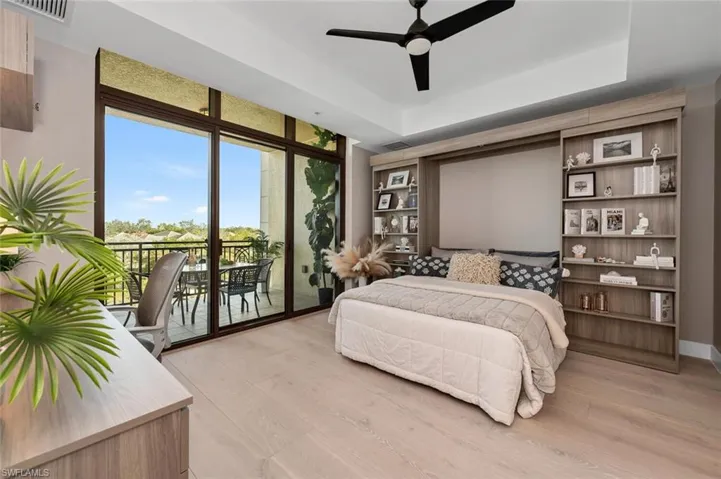Bedroom with ceiling fan, a tray ceiling, light hardwood / wood-style floors, impact resistant  windows,/sliding doors  and access to outside