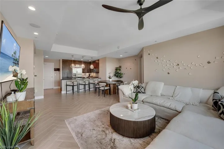 Spacious Living room featuring a raised ceiling, light flooring, and stylish ceiling fan