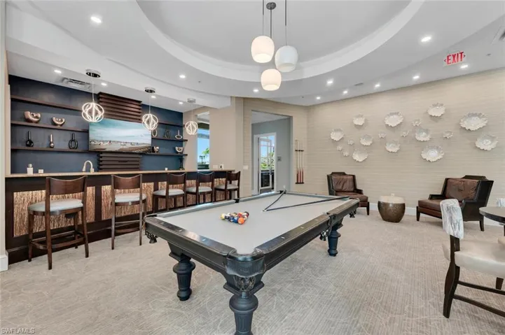 Game room featuring a raised ceiling, indoor bar, light colored carpet, and billiards