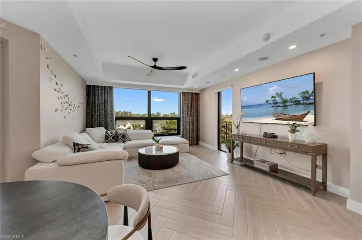 Living room with light parquet floors, a raised ceiling, and ceiling fan