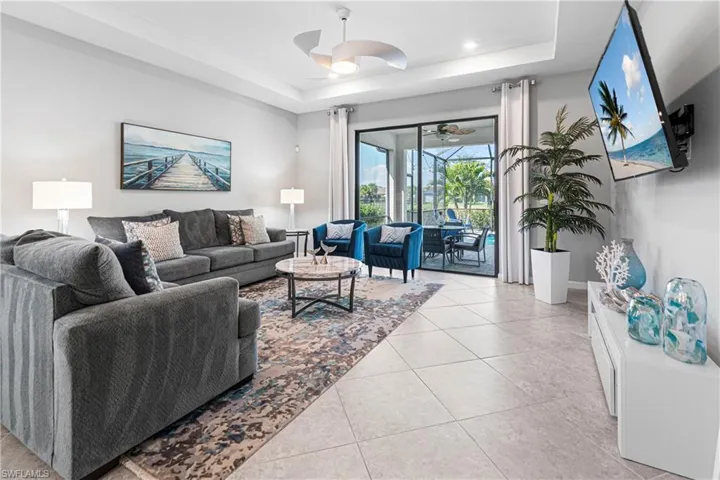Living room featuring light tile patterned floors, a raised ceiling, and ceiling fan