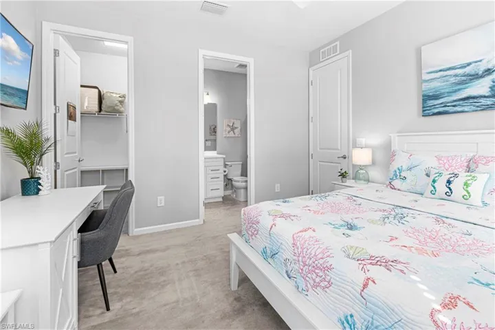 Carpeted bedroom with ensuite bath and walk-in closet