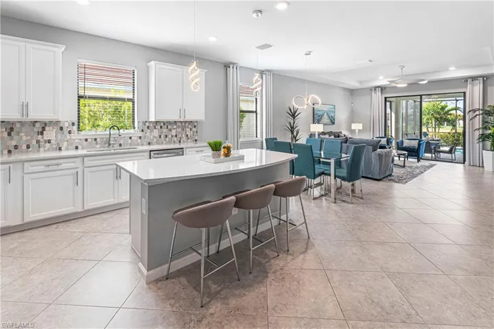 Kitchen featuring pendant lighting, sink, a kitchen island, white cabinets, and a kitchen bar