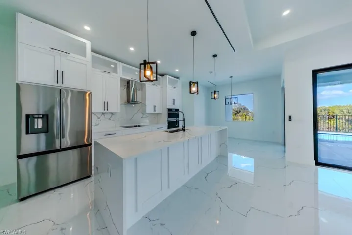 Kitchen featuring stainless steel appliances, glass fronted cabinets, light stone counters, white cabinetry, and a large island