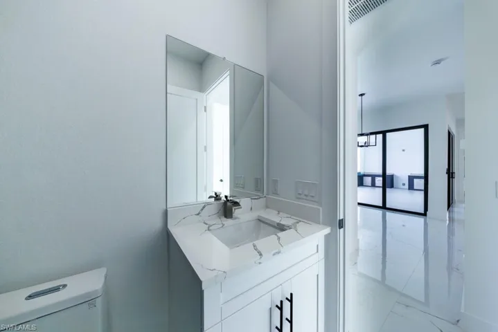 Half bathroom with vanity and light marble finish floors