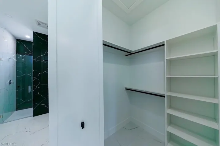 Walk in closet with light marble finish flooring