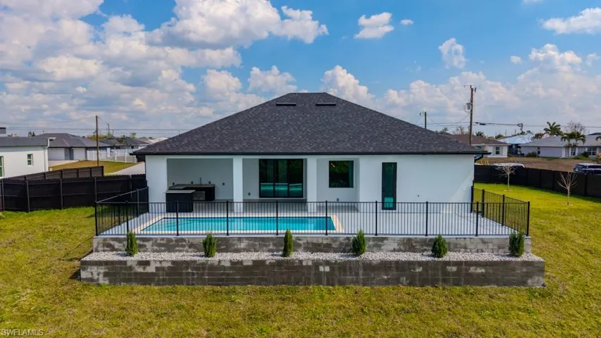 Rear view of property featuring a patio area, roof with shingles, stucco siding, a fenced backyard, and a residential view