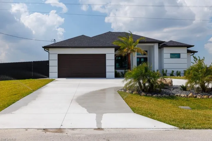 View of front of home featuring a garage, driveway, stucco siding, and roof with shingles