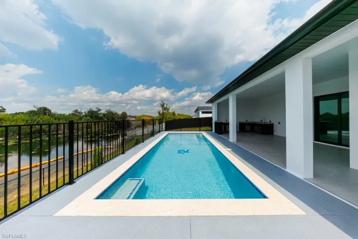 View of swimming pool with a fenced backyard, patio surround, and a water view