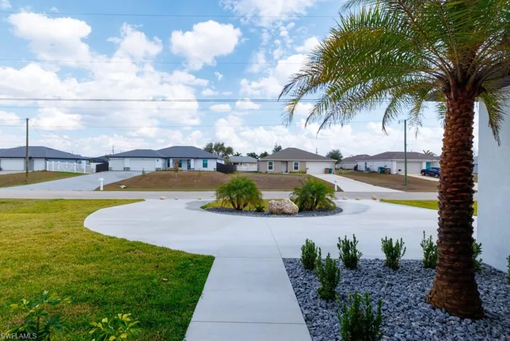 View of grassy yard featuring a residential view and curved driveway