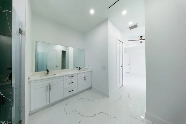 Bathroom with double vanity, a marble finish shower, recessed lighting, and ceiling fan