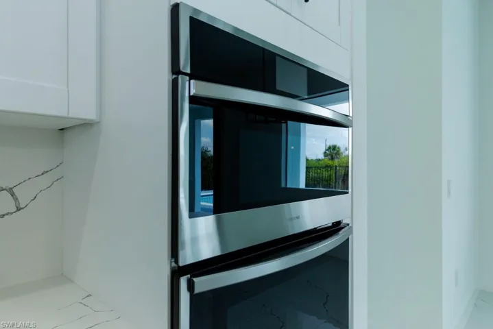 Kitchen view of stainless steel double oven and white cabinets