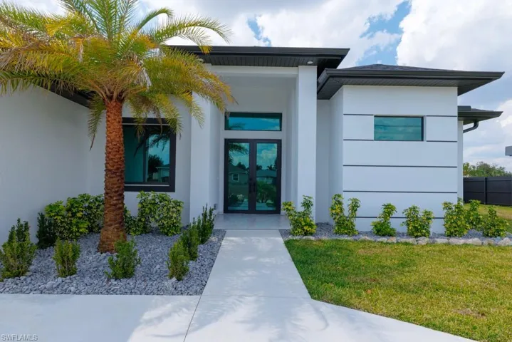 Property entrance with french doors, stucco siding, and a lawn