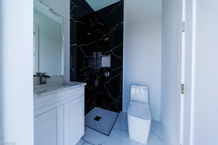 Bathroom with a marble finish shower, vanity, and light marble finish floors