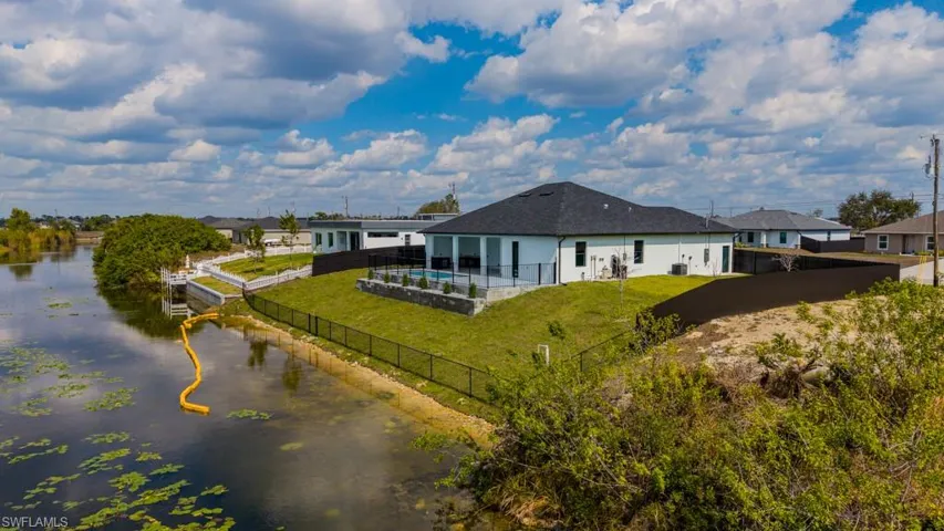Rear view of house featuring a patio area, a fenced backyard, and a water view
