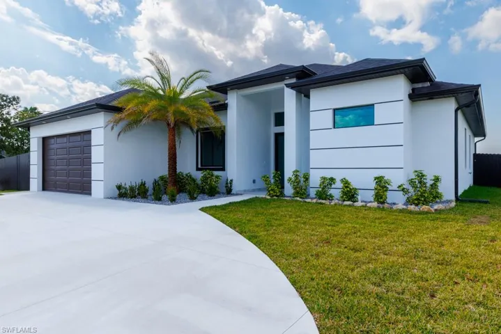 View of front of home with stucco siding, an attached garage, and driveway