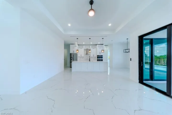 Unfurnished living room with light marble finish flooring, a raised ceiling, and recessed lighting
