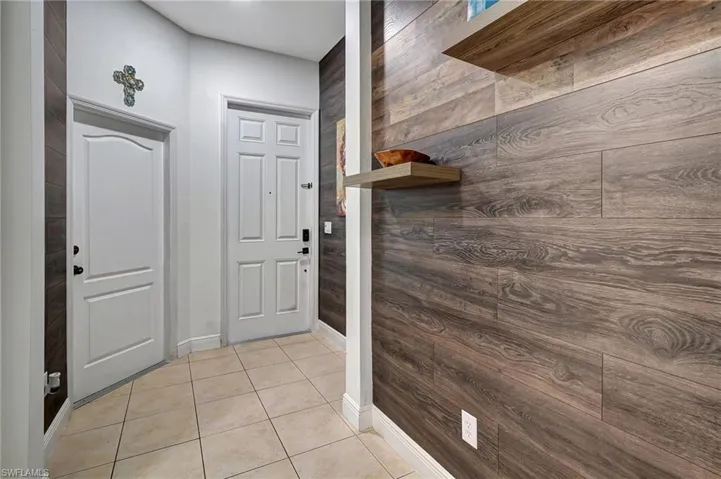 Entryway with wood walls and light tile patterned floors