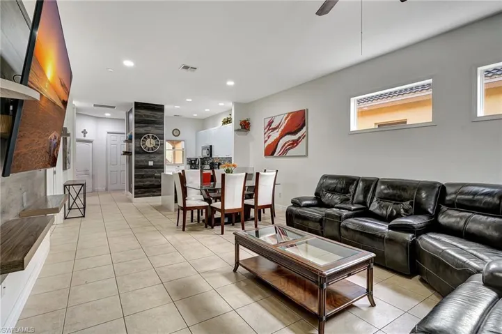Tiled living room featuring ceiling fan and a wealth of natural light