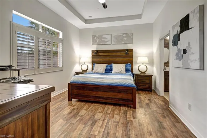 Bedroom with a raised ceiling, ceiling fan, and hardwood / wood-style flooring